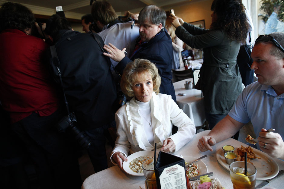 A woman eats clam chowder as media and supporters surround Republican presidential candidate Rick Santorum at a campaign event at a restaurant in Florence