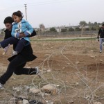 Syrians jump over barbed wire as they flee from the Syrian town of Ras al-Ain to the Turkish border town of Ceylanpinar