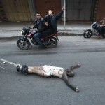 Palestinian gunmen ride motorcycles as they drag  the body of a man, who was suspected of working for Israel, in Gaza City
