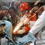 Fellow workers, a firefighter and doctors work together to cut steel bars which were pierced through a worker's body during an operation at a hospital in Hangzhou