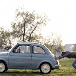 Woman pushes her Fiat 500 car as her dog sits inside, in neighbourhood of Rome