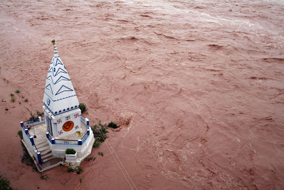 A temple stands amid the waters of the flooded river Tawi after heavy rains in Jammu