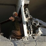 Palestinian man checks his damaged house after Israeli air strikes in Gaza