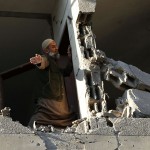 Palestinian man checks his damaged house after Israeli air strikes in Gaza