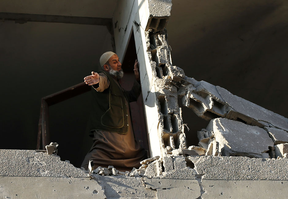 Palestinian man checks his damaged house after Israeli air strikes in Gaza