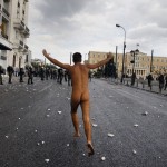 A naked protester runs past the parliament in Syntagma Square in Athens during a violent protest against the visit of Germany's Chancellor Angela Merkel