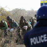 A policeman fires at protesting miners outside a South African mine in Rustenburg