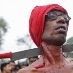 A Hindu devotee with his neck pierced with a knife attends Chadak rituals at Krishanadevpur village
