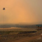 A firefighting helicopter fills a bucket of water in heavy smoke as the North Merna wildfire burns in the Bridger National Forest west of the town of Pinedale in Sublette County, Wyoming