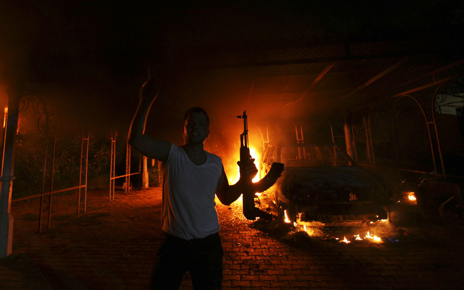 A protester reacts as the U.S. Consulate in Benghazi is seen in flames