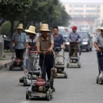 Residents push lawn mowers on a street in Nanjie village of Luohe city