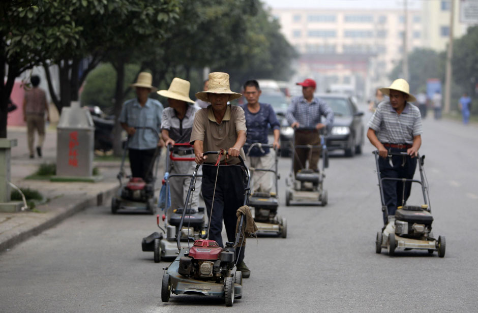 Residents push lawn mowers on a street in Nanjie village of Luohe city