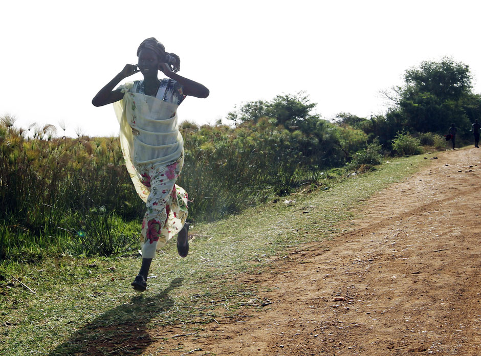 A woman runs along a road during an air strike by the Sudanese air force in Rubkona near Bentiu