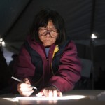 Woman uses shaft of sunlight to see her ballot as she votes in polling site during U.S. presidential election in New York