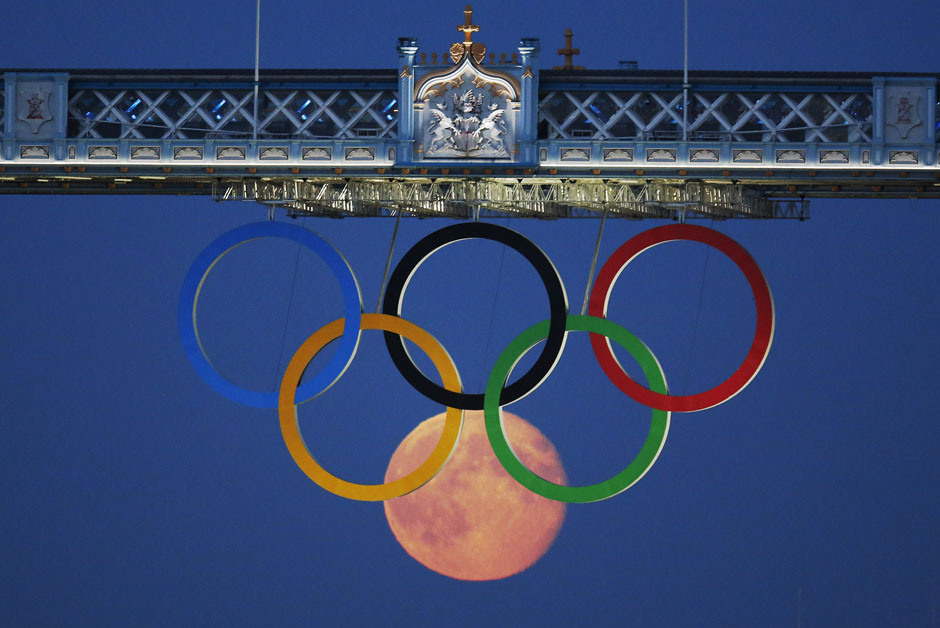 The full moon rises through the Olympic Rings hanging beneath Tower Bridge during the London 2012 Olympic Games