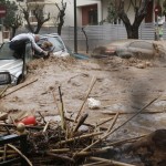 A woman is rescued from flood waters by a resident standing on top of her car during heavy rain in Chalandri suburb north of Athens