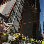 An ironworker uses a line to steady the final piece of a spire, affixed with a U.S. flag, before it is lifted to the top of One World Trade Center in New York