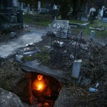 Bratislav Stojanovic, a homeless man, hold candles as he sits in a tomb where he lives in southern Serbian town of Nis