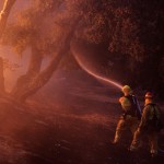 Firefighters spray water near a burning house in the Twin Pines Road area at the Silver Fire near Banning, California.