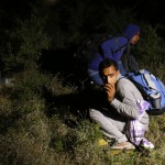 Migrants sit on the ground after being apprehended by the Serbian border police, having illegally entered the country from Macedonia, near Presevo