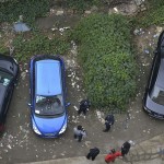 Police and bystanders look at a car which is covered with vegetation after it was left parked at a neighbourhood for more than a year, in Chengdu