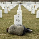 A woman lies down in front of the grave of her brother at Arlington National Cemetery near Washington