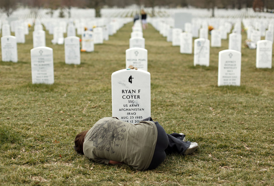 A woman lies down in front of the grave of her brother at Arlington National Cemetery near Washington