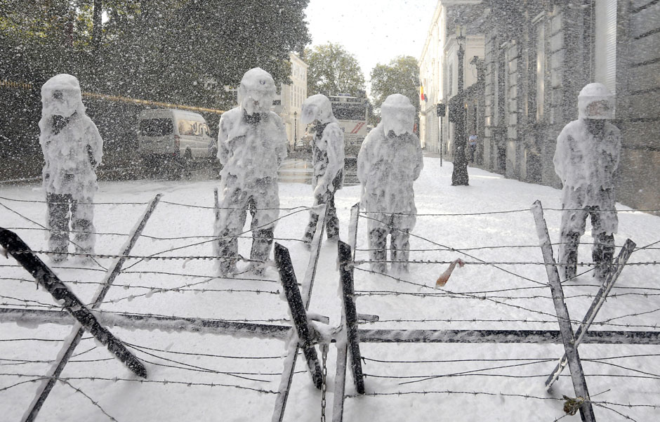 Belgian riot police are covered with foam sprayed by Belgian firefighters during a protest for better work conditions in central Brussels