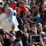 Pope Francis waves as he tries to grab handkerchief thrown by faithful as he arrives to lead his Wednesday general audience in Saint Peter's square at the Vatican