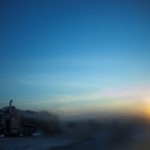 A truck parked along side of a road is pictured through a frosted window during sunrise in Williston