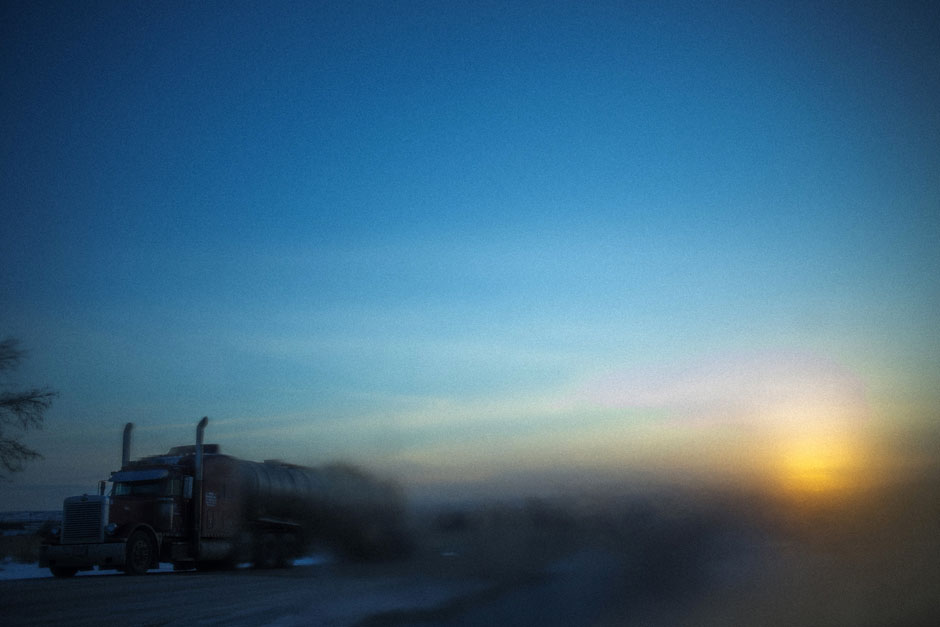 A truck parked along side of a road is pictured through a frosted window during sunrise in Williston