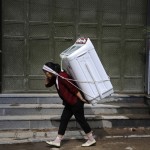 A woman carries home a washing machine in Dali