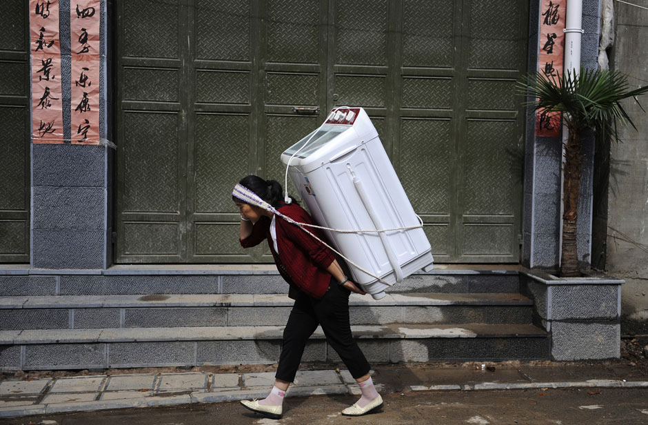 A woman carries home a washing machine in Dali