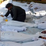 A man holds the body of a dead child among bodies of people activists say were killed by nerve gas in the Ghouta region, in the Duma neighbourhood of Damascus