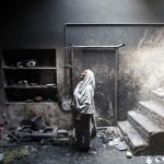 A woman looks at her dead pet bird in a cage at her home, which was burnt by a mob two days earlier, in Badami Bagh, Lahore