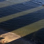 Men play soccer between the shadows of buildings in Boa Viagem Beach in Recife