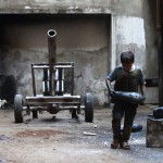 Issa carries a mortar shell in a weapons factory of the Free Syrian Army in Aleppo