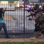 A man backs away as law enforcement officials close in on him and eventually detain him during protests over the death of Michael Brown, an unarmed black teenager killed by a police officer, in Ferguson, Mo.