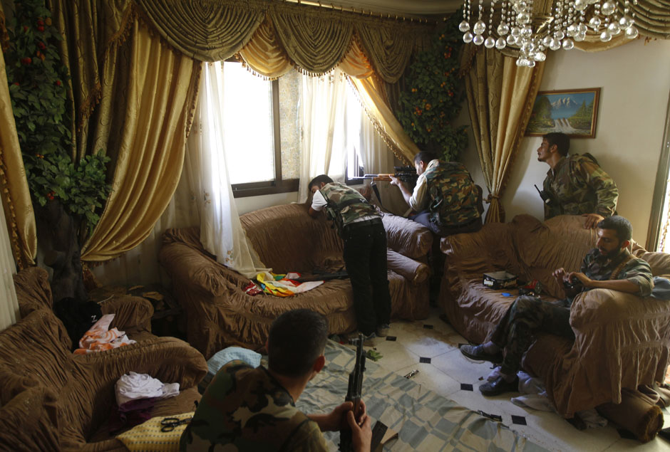 A Free Syrian Army fighter fires his sniper rifle from a house in Aleppo