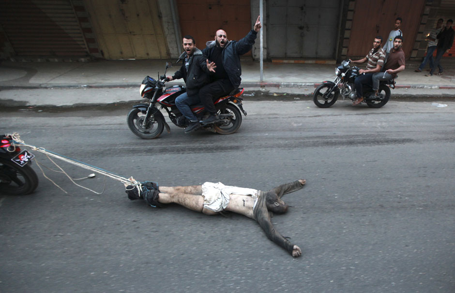 Palestinian gunmen ride motorcycles as they drag  the body of a man, who was suspected of working for Israel, in Gaza City