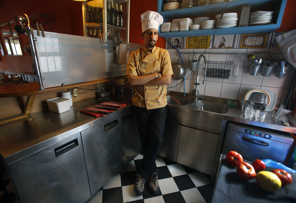 Manolis Ouranos, a 30 year-old cook, poses for a picture in the Mavros Gatos tavern in Psiri neighboorhood in central Athens