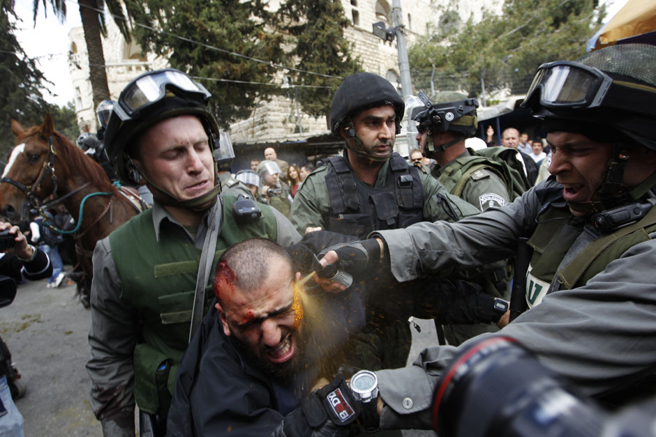 Israeli border police officers use pepper spray as they detain an injured Palestinian protester during clashes outside Jerusalem's Old City