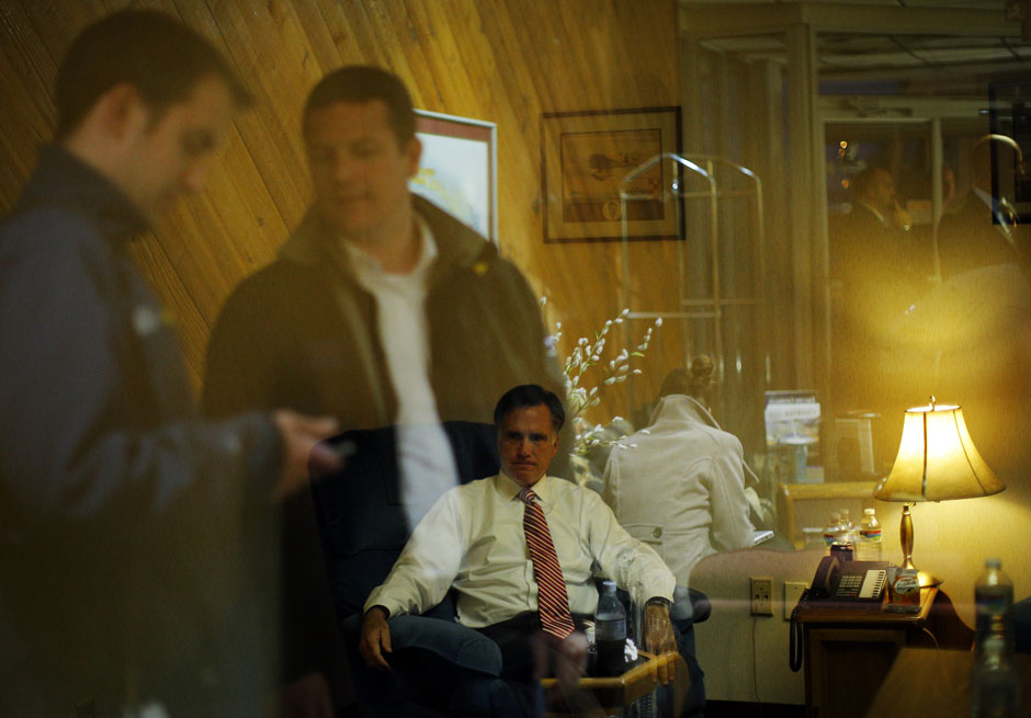 Staff members reflected in the window on the room where Republican presidential nominee Mitt Romney works before a campaign rally in North Canton