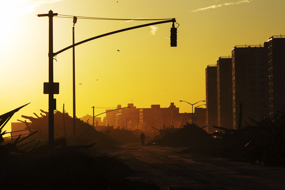 A man walks down Shore Front Parkway surrounded by debris pushed onto the streets by hurricane Sandy in the Queens borough region of the Rockaways in New York