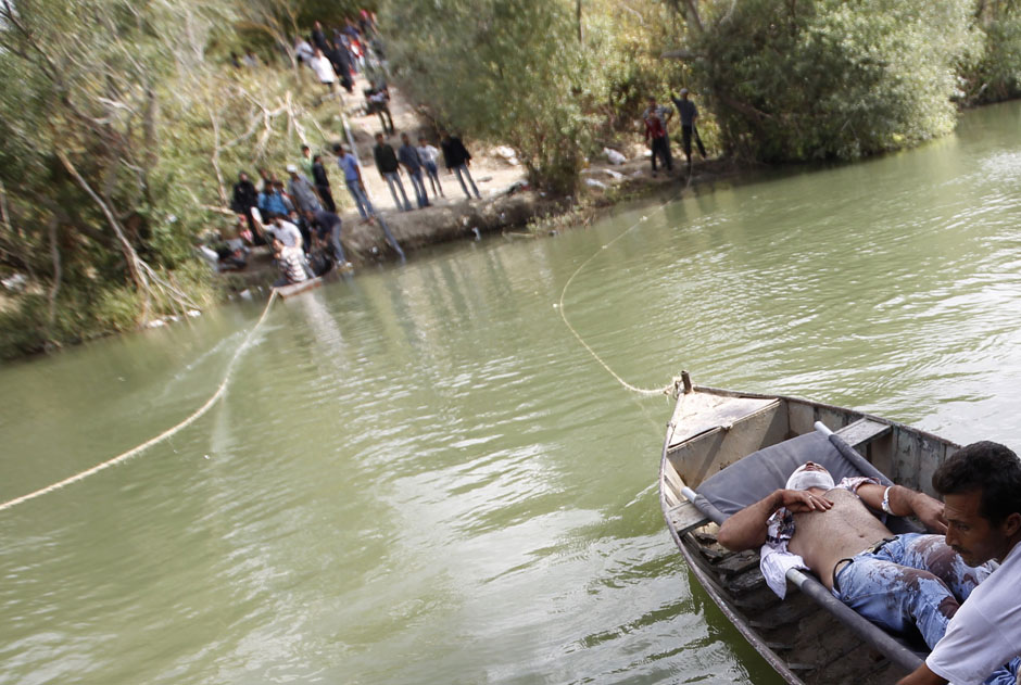 A wounded Syrian man lies on a boat as he is transferred to Turkey over the Orontes river on the Turkish-Syrian border near the village of Hacipasa in Hatay province