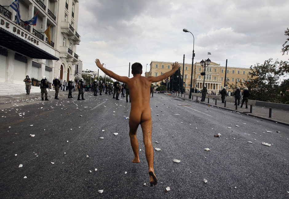 A naked protester runs past the parliament in Syntagma Square in Athens during a violent protest against the visit of Germany's Chancellor Angela Merkel