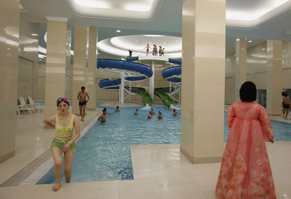 A woman in traditional Korean costume watches as a student leaves a swimming pool of Kim Il-sung University in Pyongyang