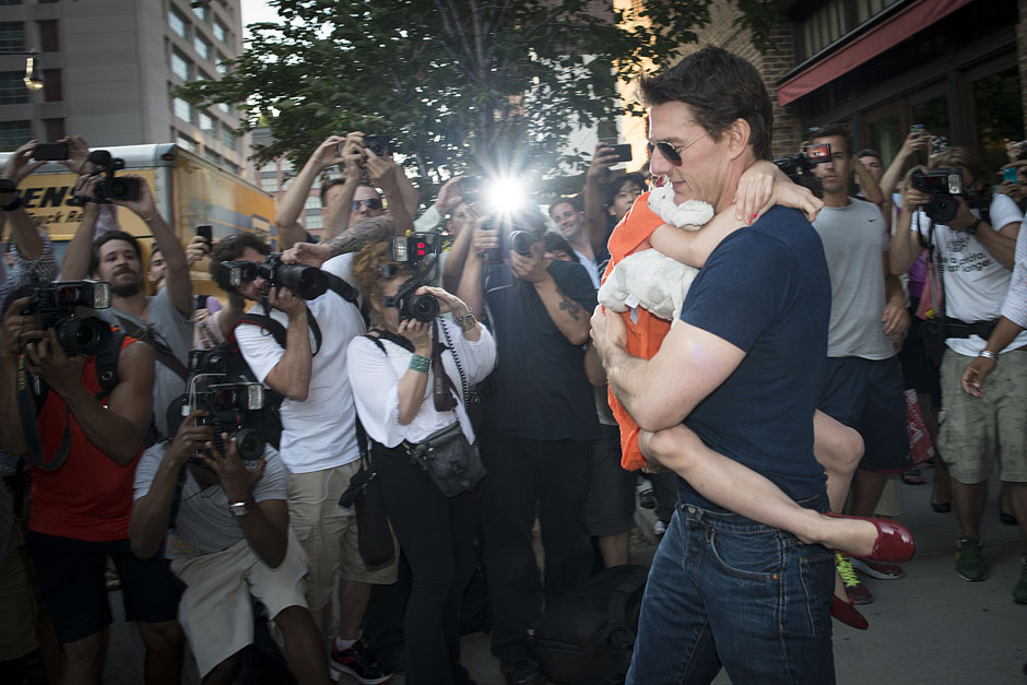 Actor Tom Cruise carries his daughter Suri past a group of photographers as they make their way from a hotel