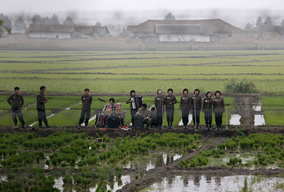 A music group performs on a path amid fields to greet the farmers at Hwanggumpyong Island