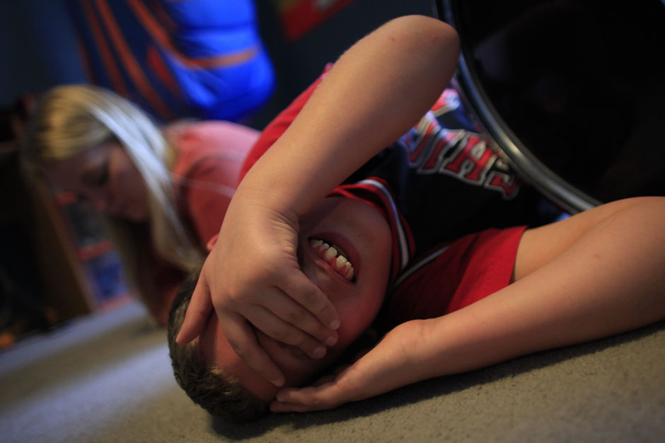 Parker Roos, who suffers from Fragile X, rolls around on the floor after getting into an argument with his sister at their home in Canton, Illinois